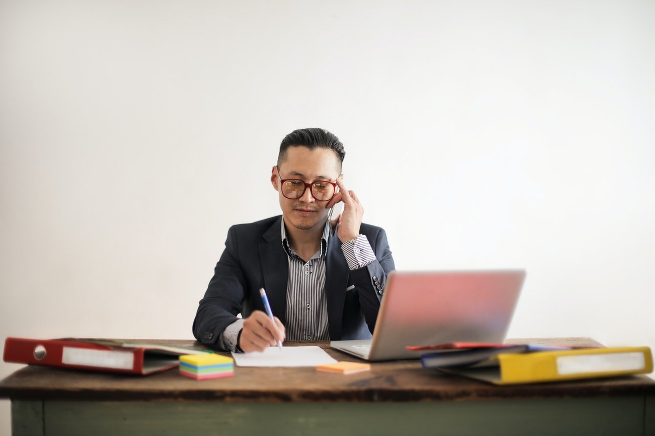 a man sitting in his office while talking on the phone