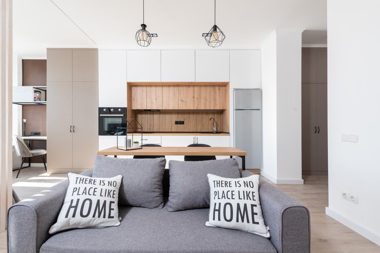 A room with sofa next to open kitchen