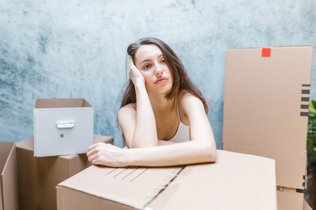 a woman being sad while leaning on a cardboard box