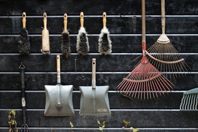 Gardening tools hanging on a black brick wall prepared for packing the gardening tools for a move.