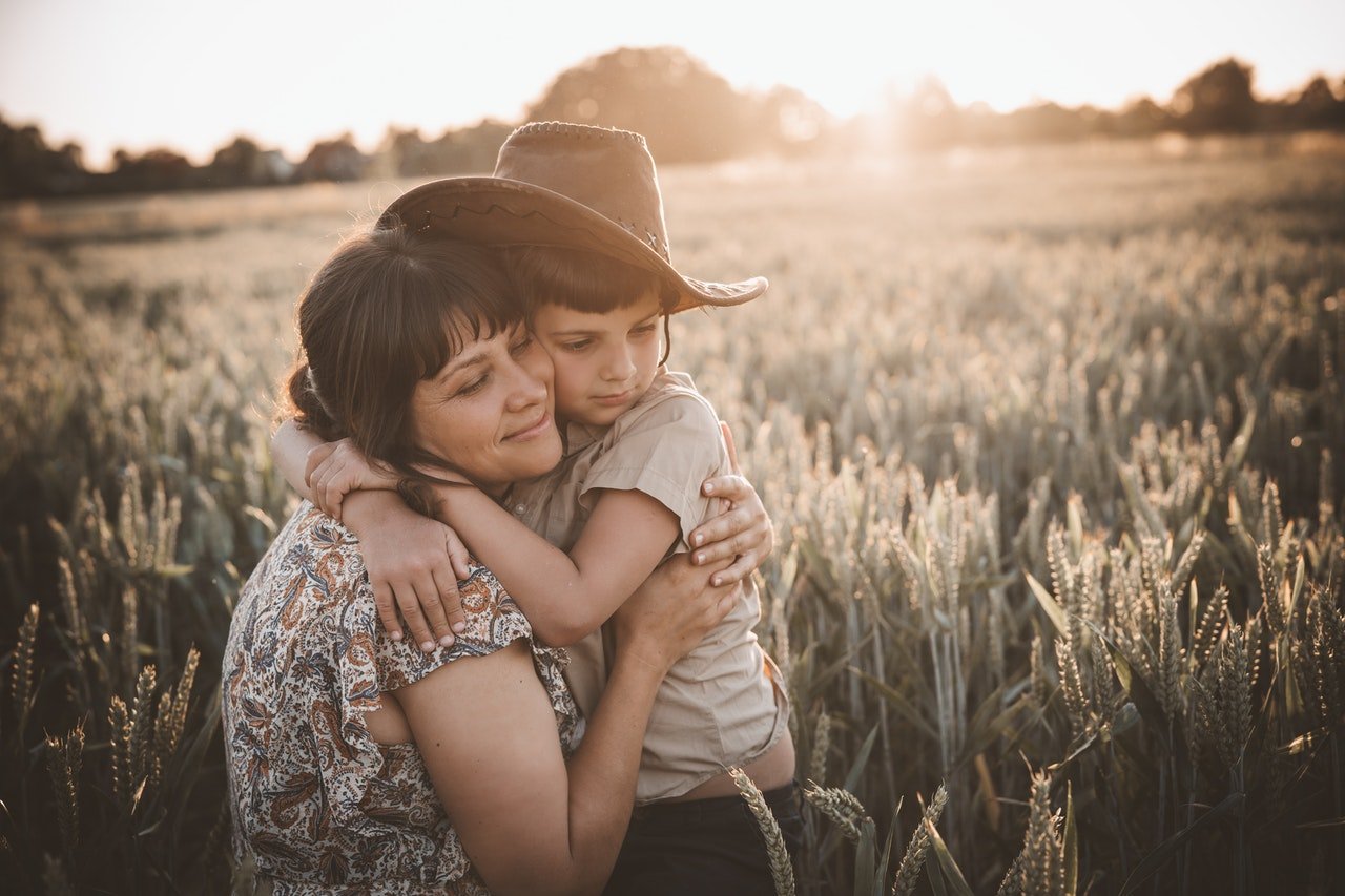 Loving mother hugging her son in a grassy field