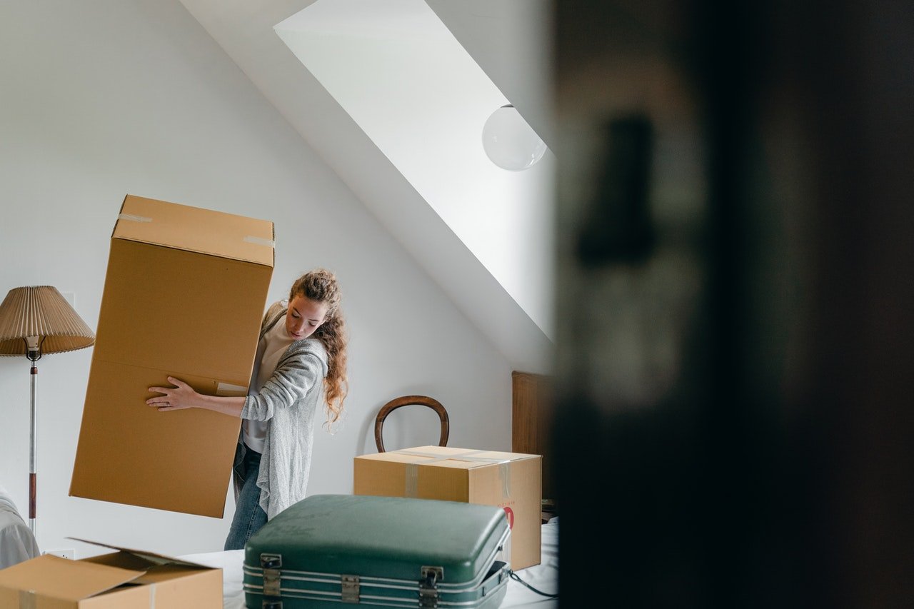 Woman carrying boxes while packing a studio apartment