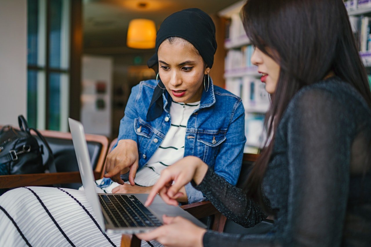 Two women looking at a laptop while searching for moving referrals