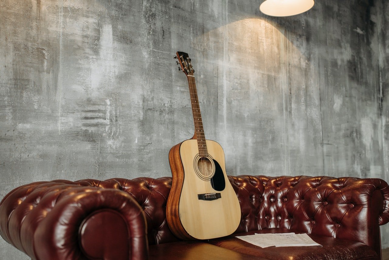 a wodden guitar on a leather couch
