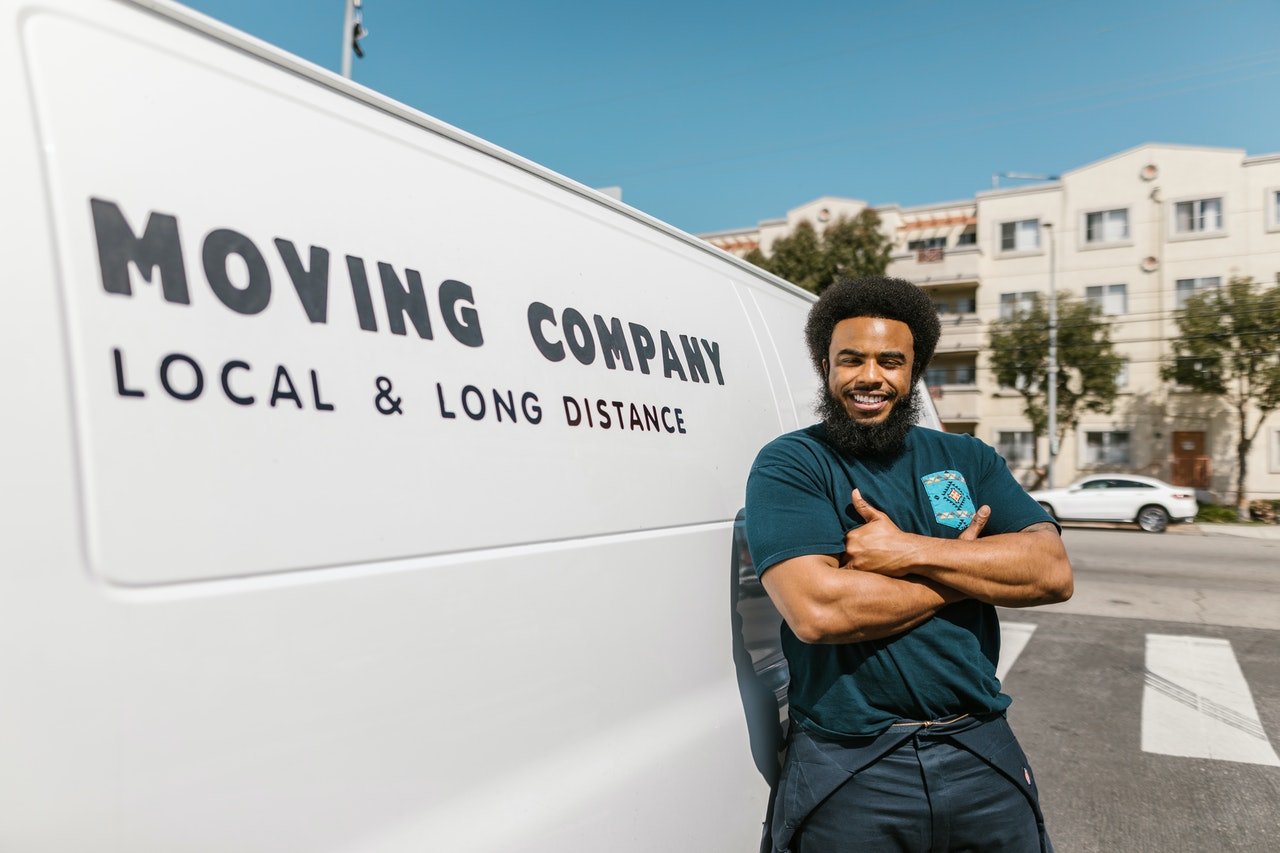 a mover posing in front of his white moving van