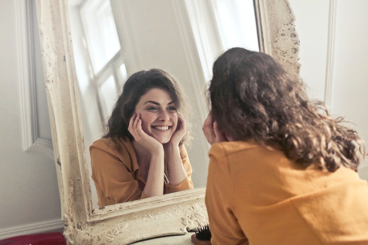 A woman looking in the mirror, smiling