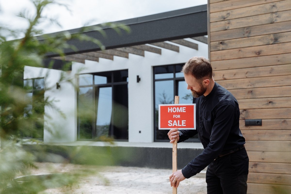 A man puting up a home for sale sign