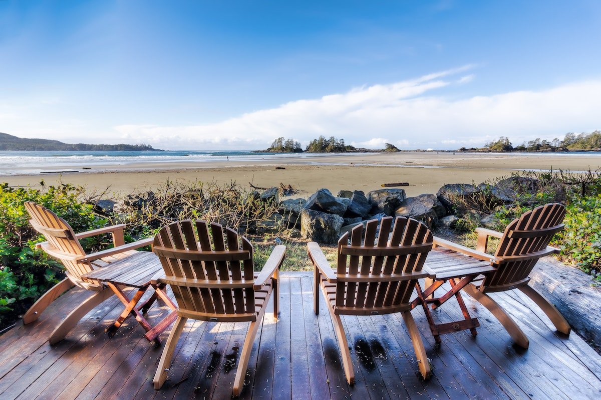 Four Brown Adirondack Chairs On Porch.