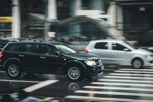 Black SUV beside grey SUV crossing the pedestrian line