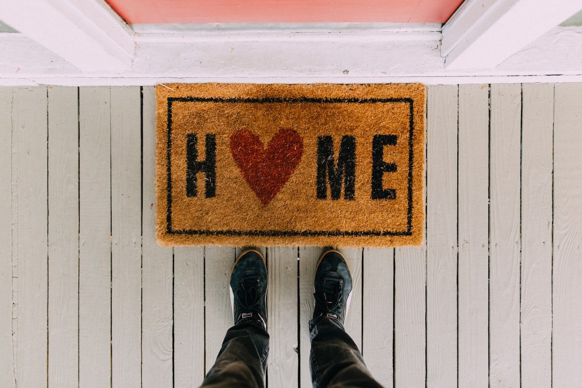 a person standing above a welcome mat that says 'home' on it