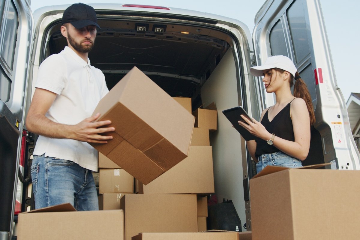man and woman packing cardboard boxes into the van, talking about when to hire a white glove moving company