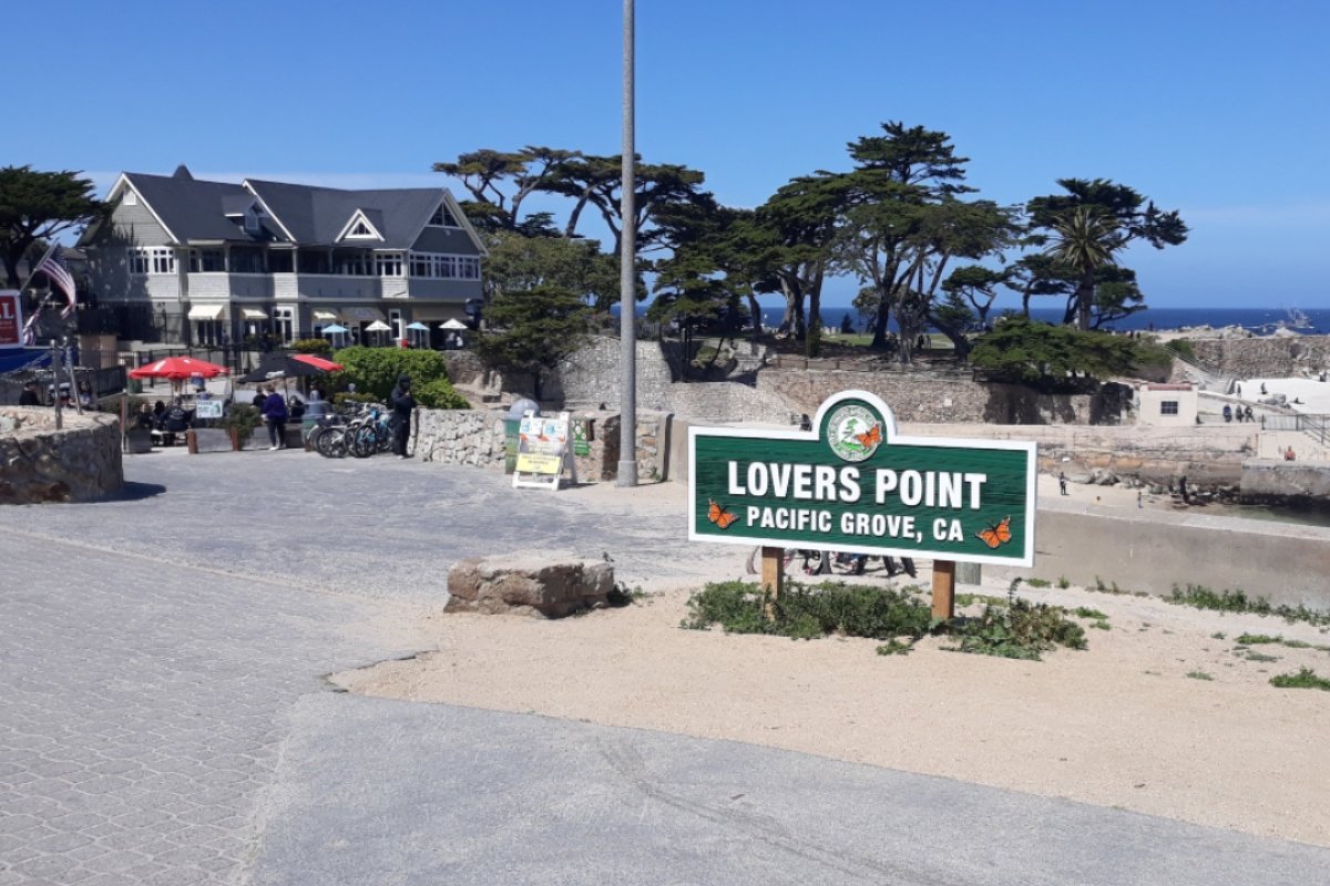 Green and white sign in front of trees and house making people wonder - Is Pacific Grove a good place to retire