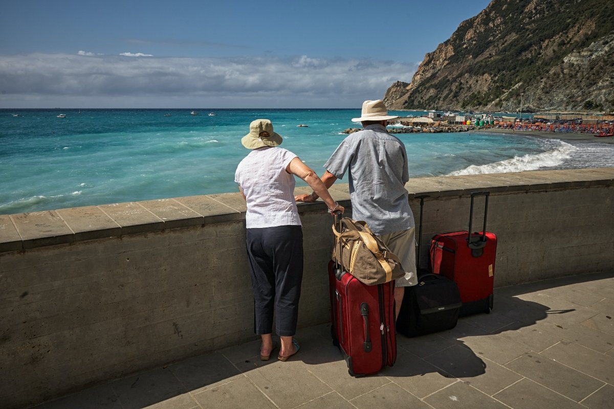 Man and woman standing beside concrete seawall looking at the beach before leaving California as a senior