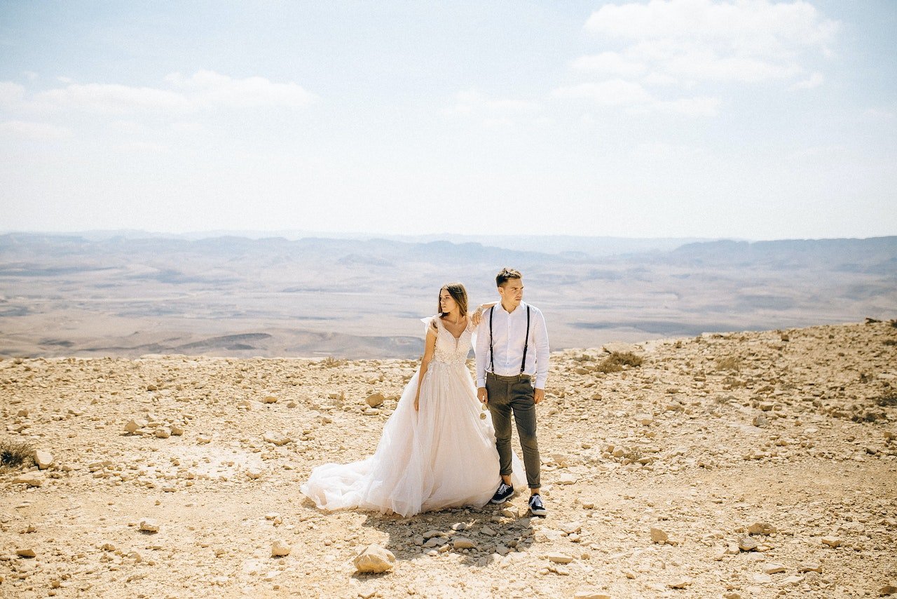 a woman in a white dress and a man in the middle of the desert