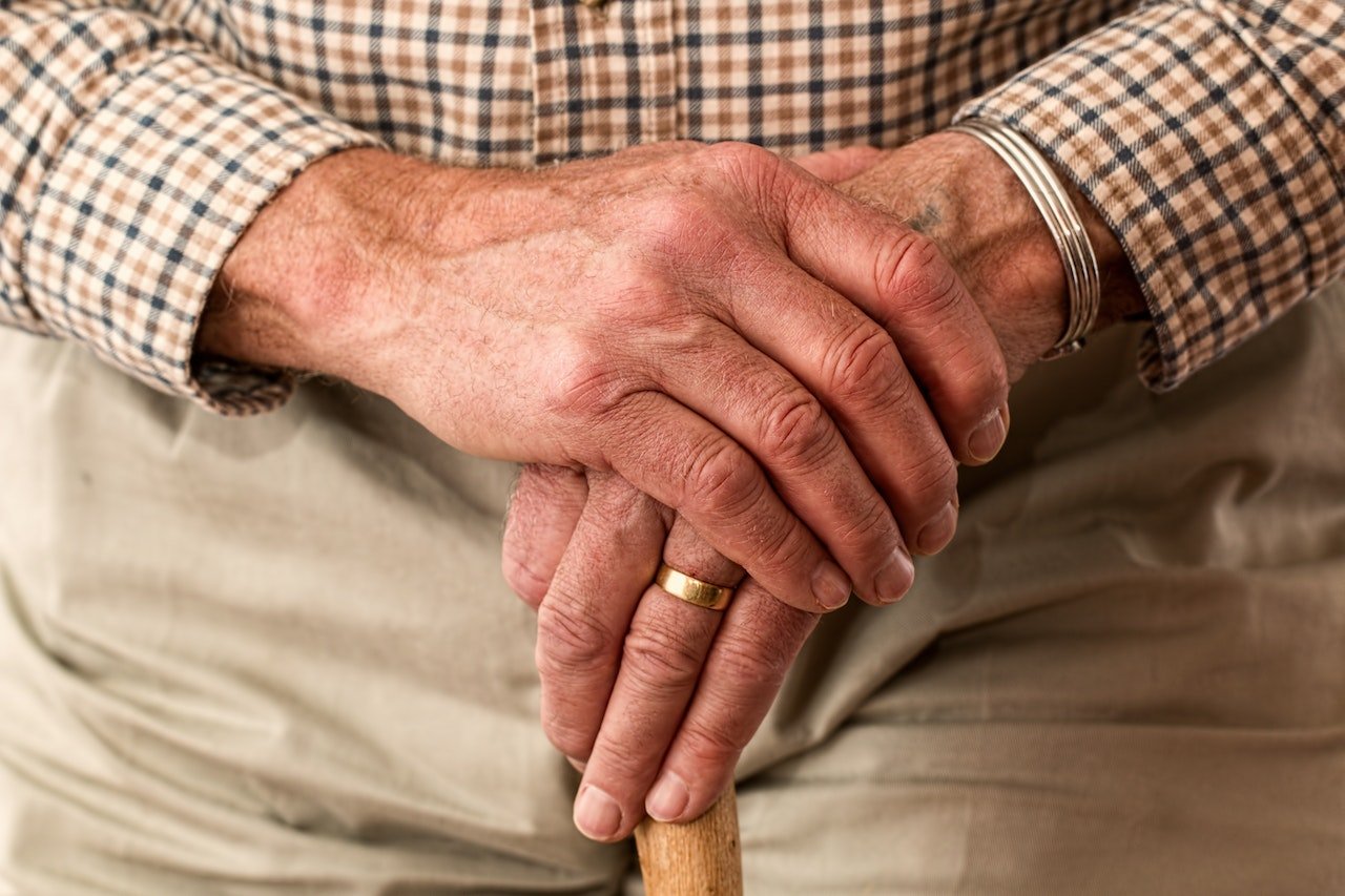 an elderly person's hands holding a cane