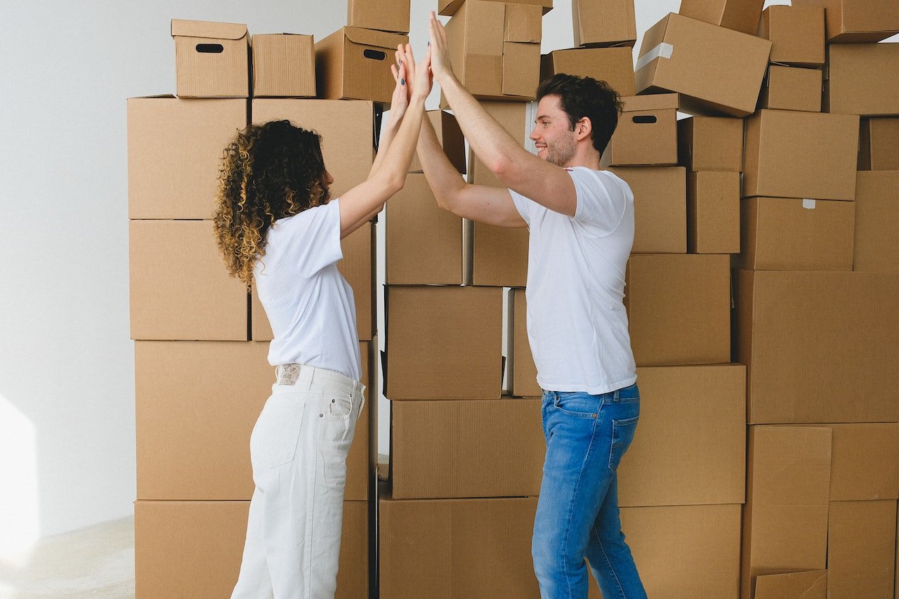 a man and a woman holding hands in front of cardboard boxes