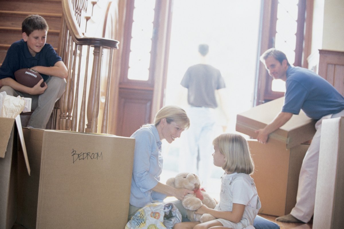 Family sitting between boxes on moving day