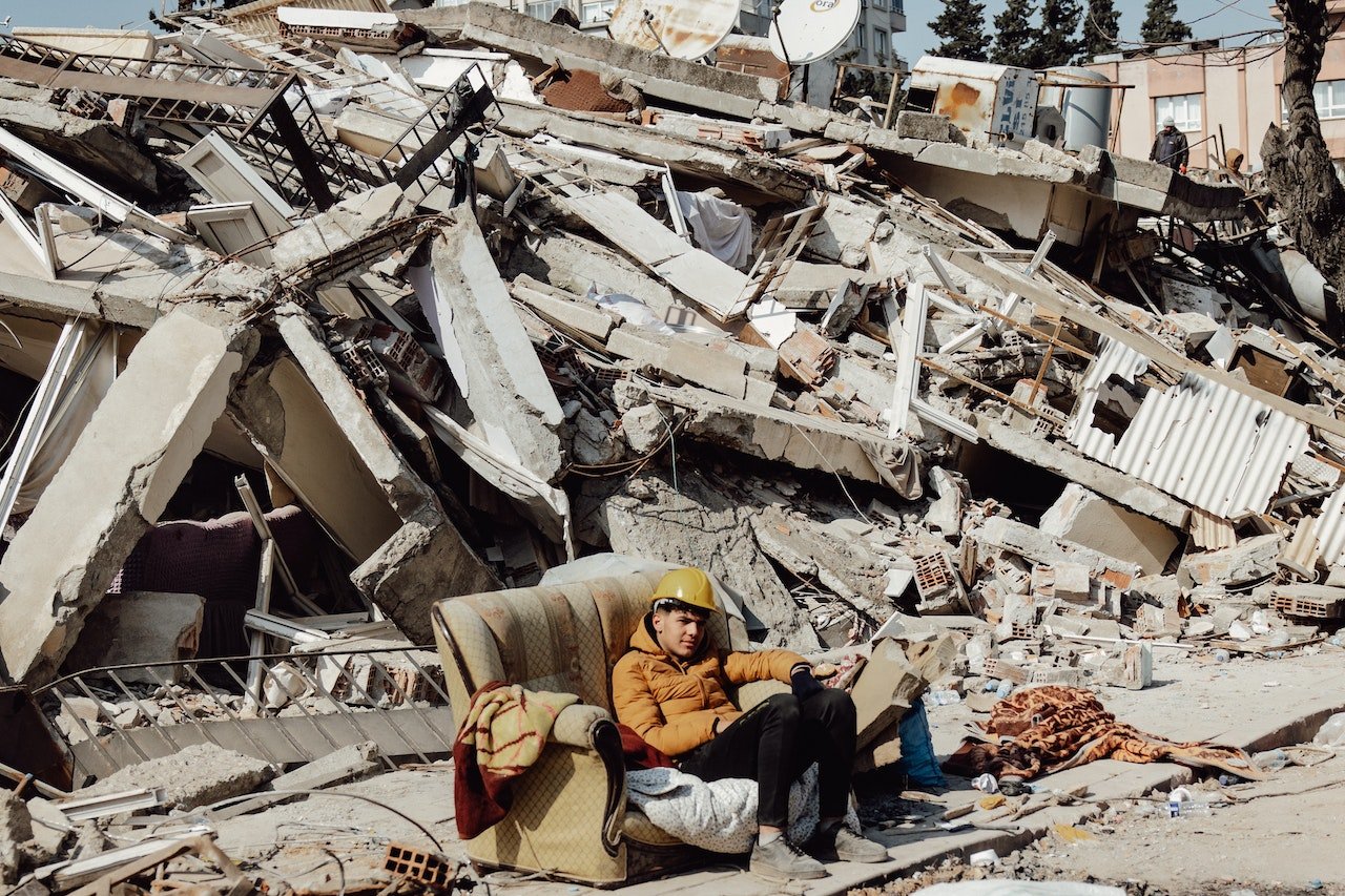 a young man sitting on the sofa behind demolished building