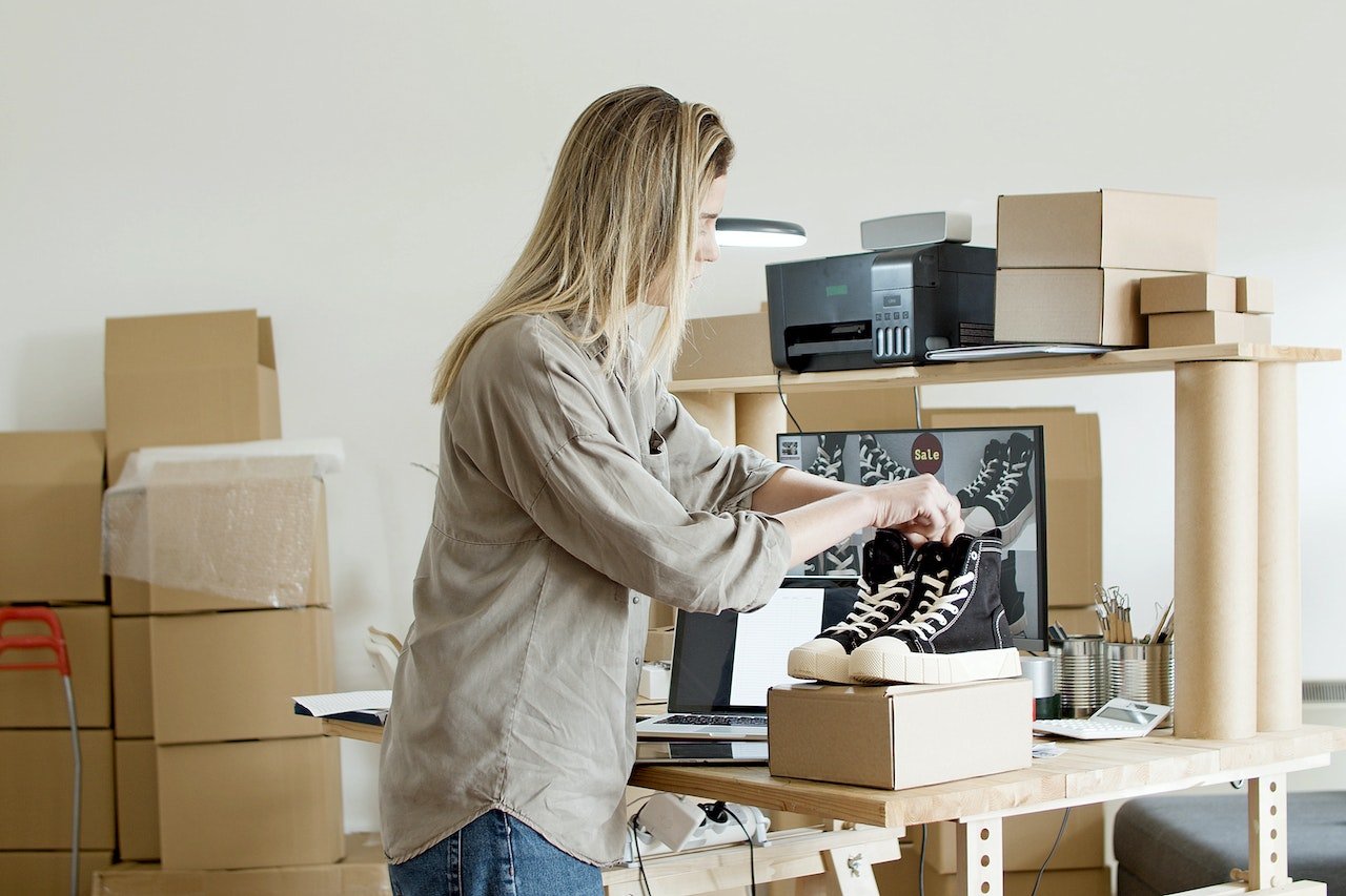 woman packing sneakers into cardboard box