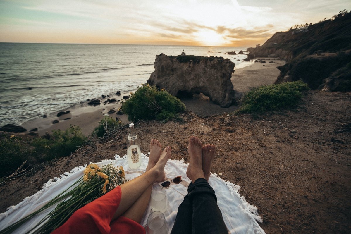 two persons lying on the white blanket near the beach