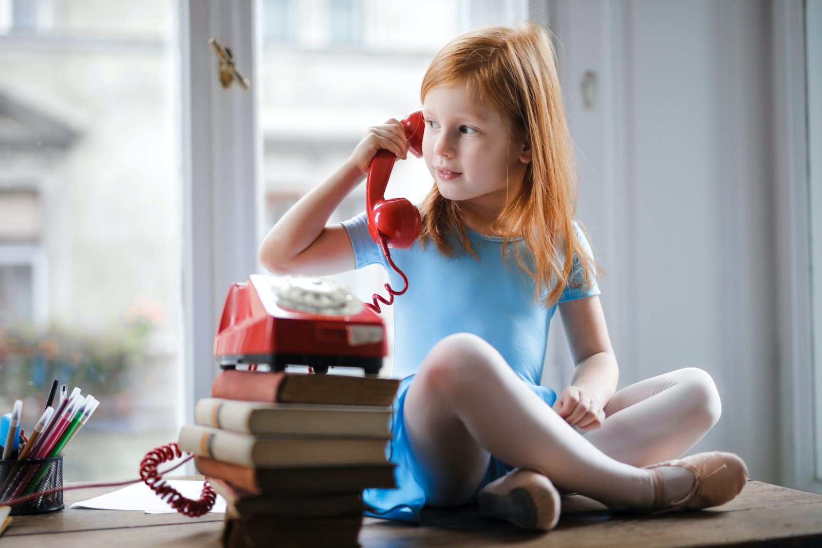 A little girl sitting by the books.
