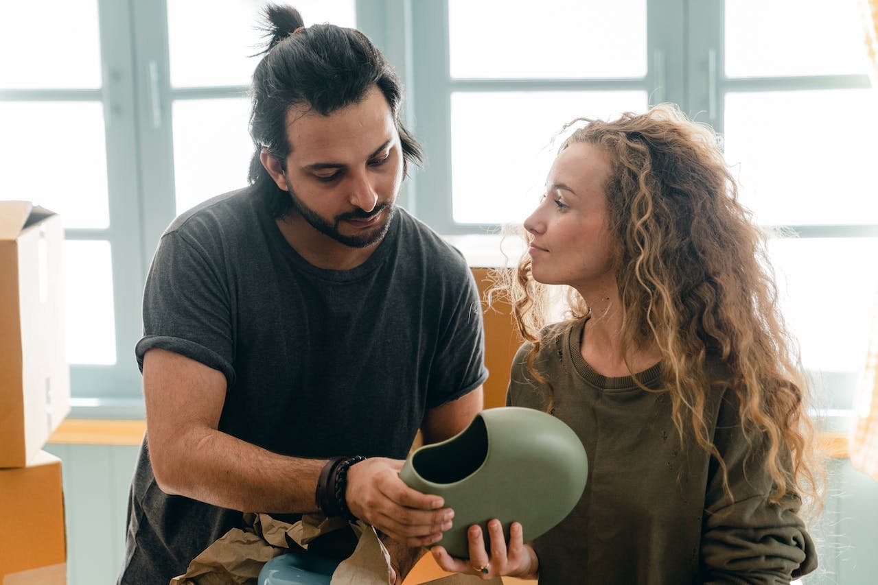 a man holding a green vase and a woman looking at him