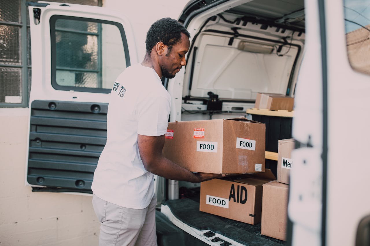 a man in white placing boxes into a white van