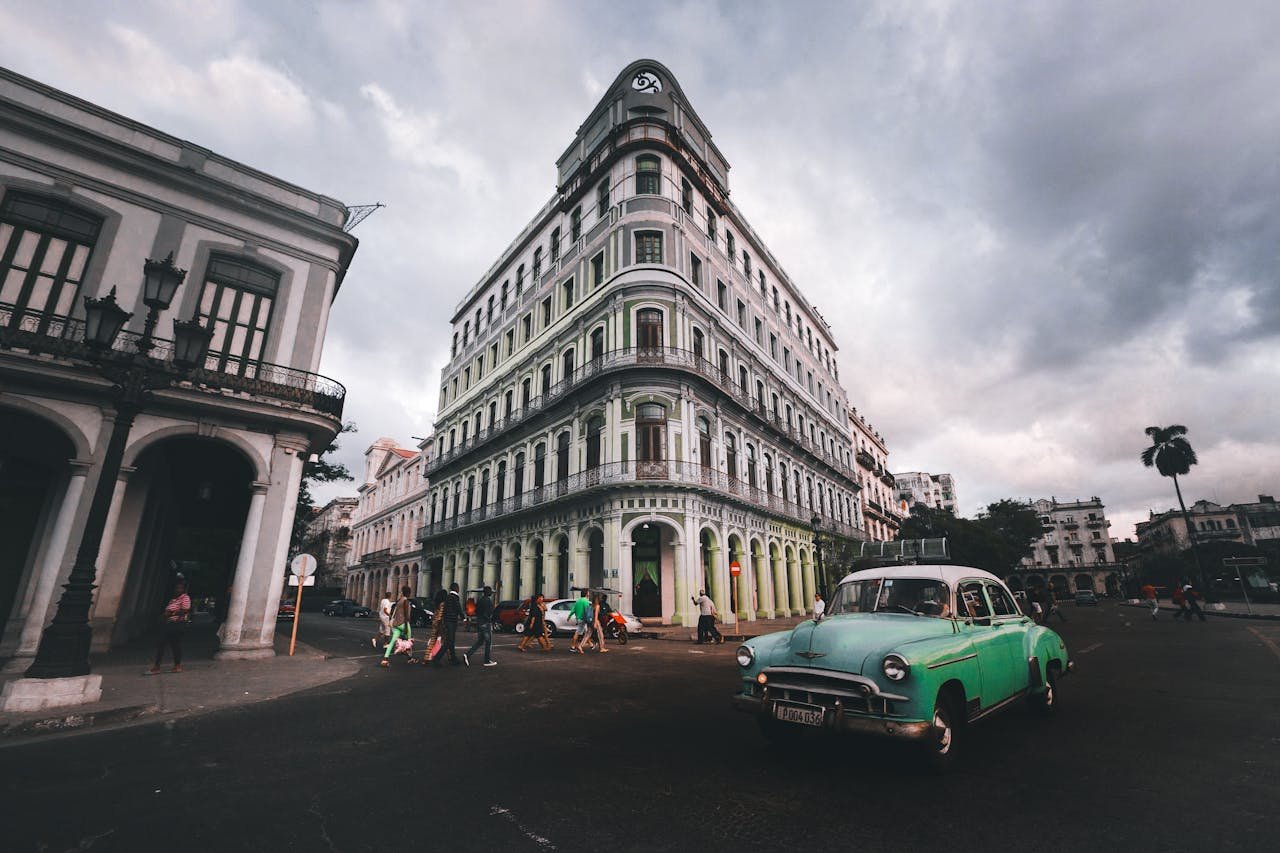 green car on a road in front of the building
