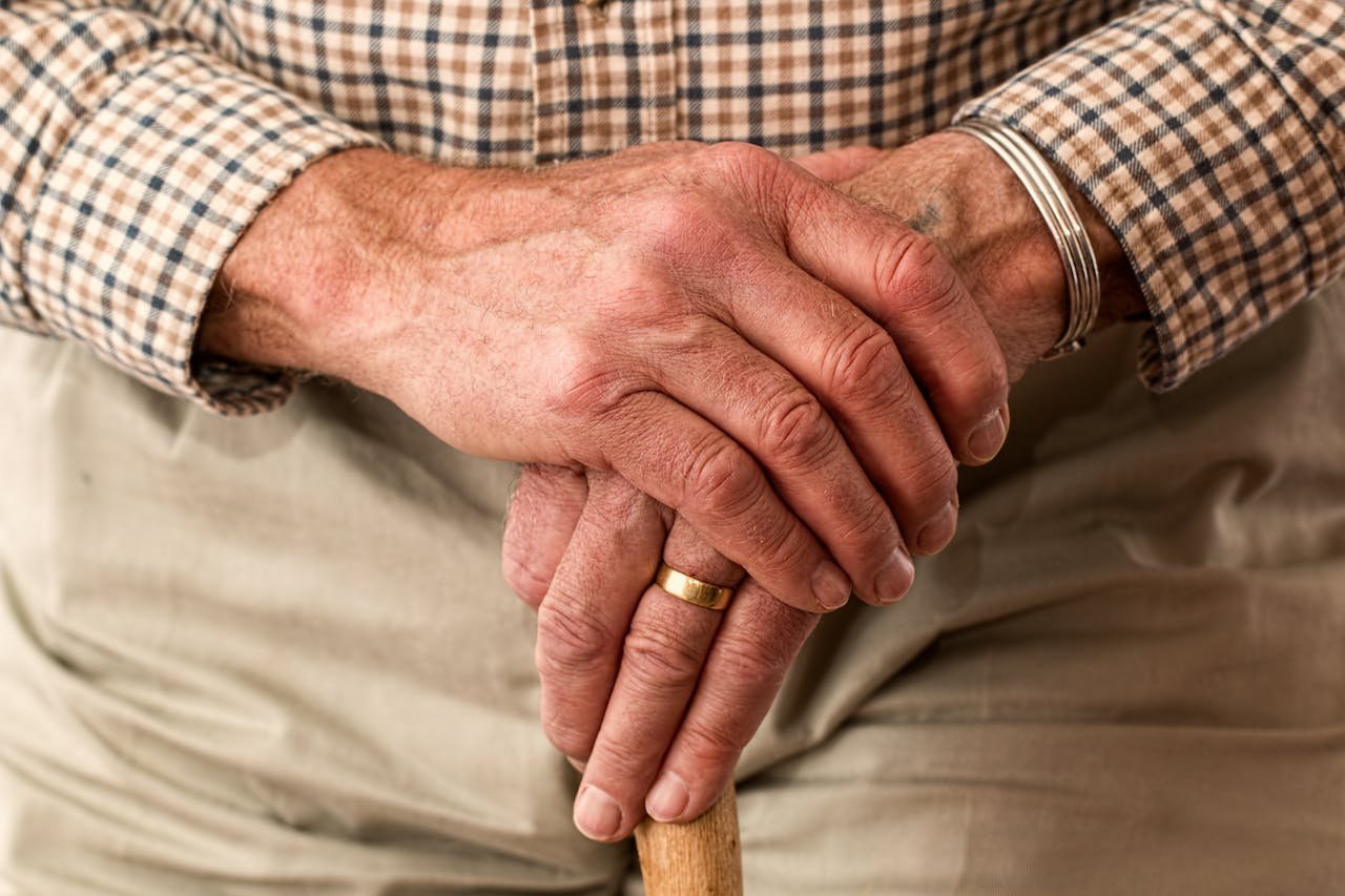 an old person holding hands onto a cane