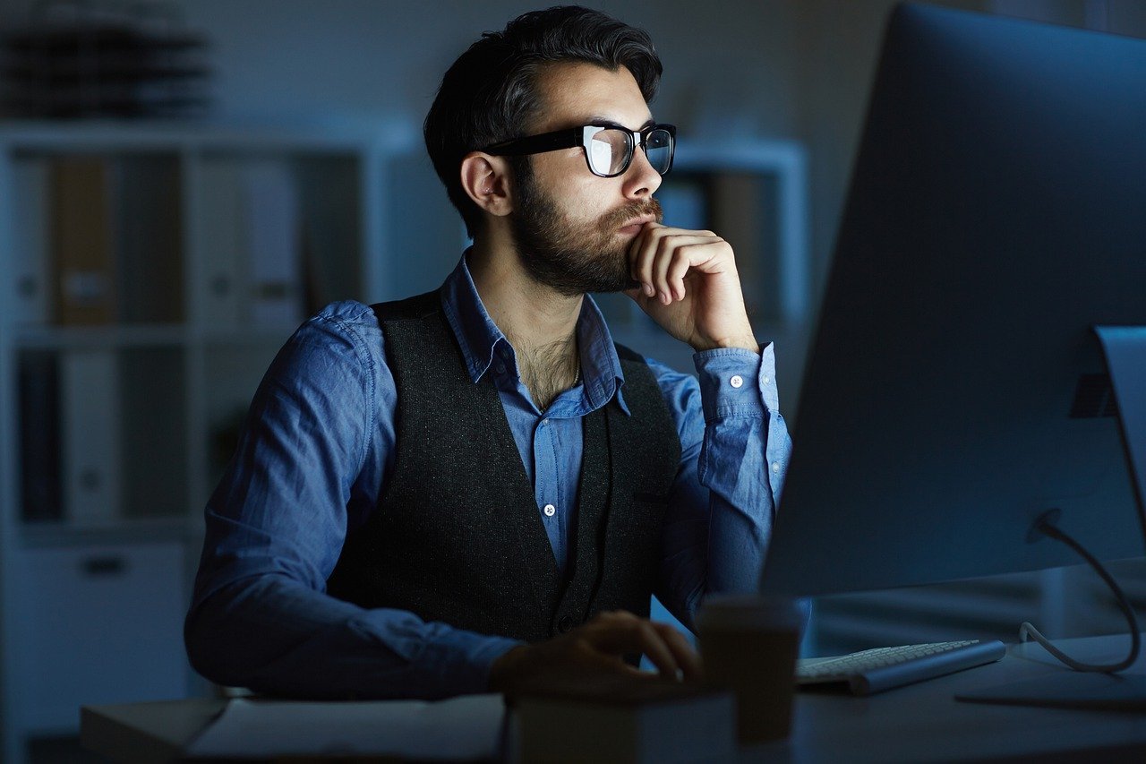 a man with glasses browsing on the laptop