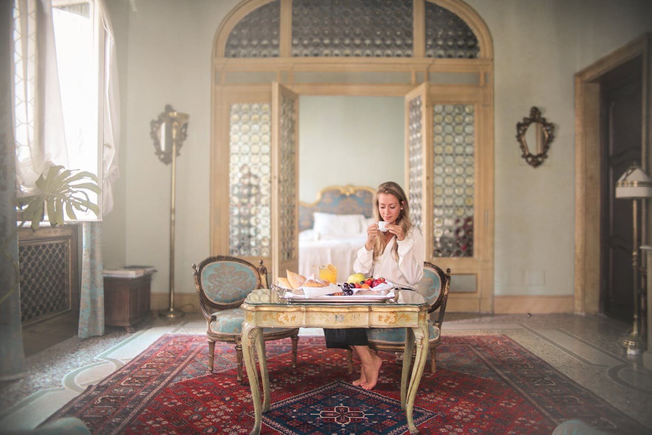 a woman drinks from a cup while sitting at a table