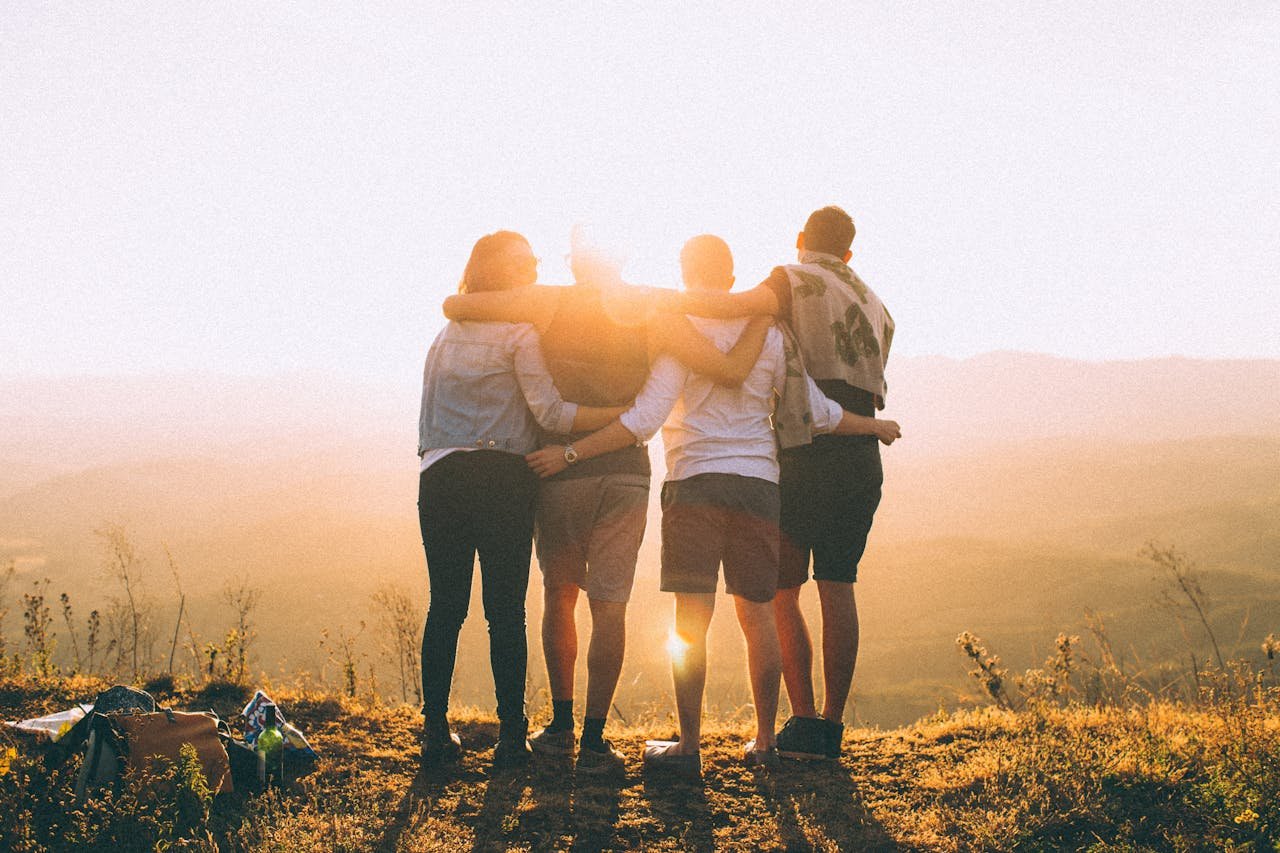 four persons standing on a cliff in the sun