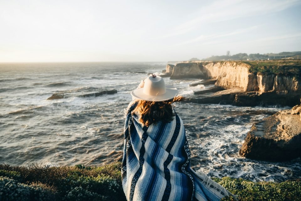 Woman sitting on a cliff overlooking the ocean