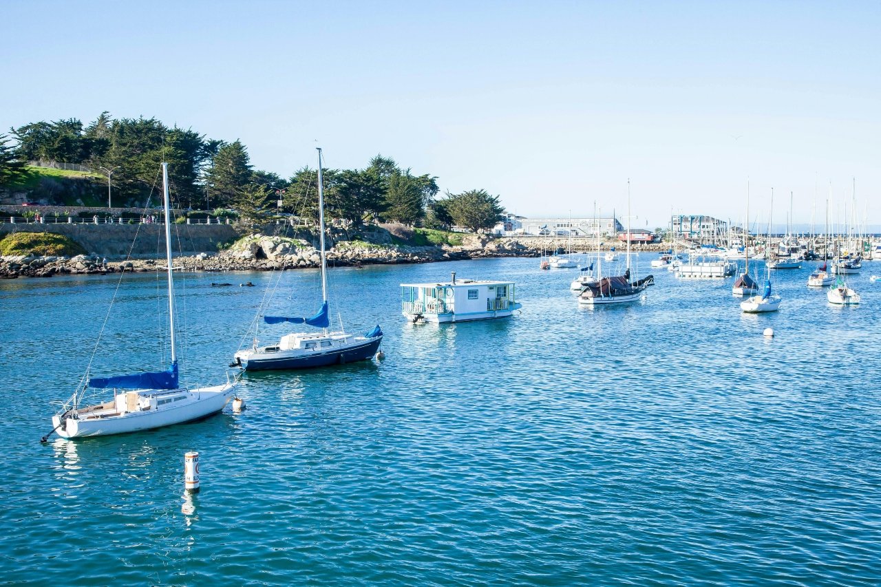 Scenic view of Monterey’s coastline with blue ocean, rocky shores, and vibrant cityscape under a clear sky.